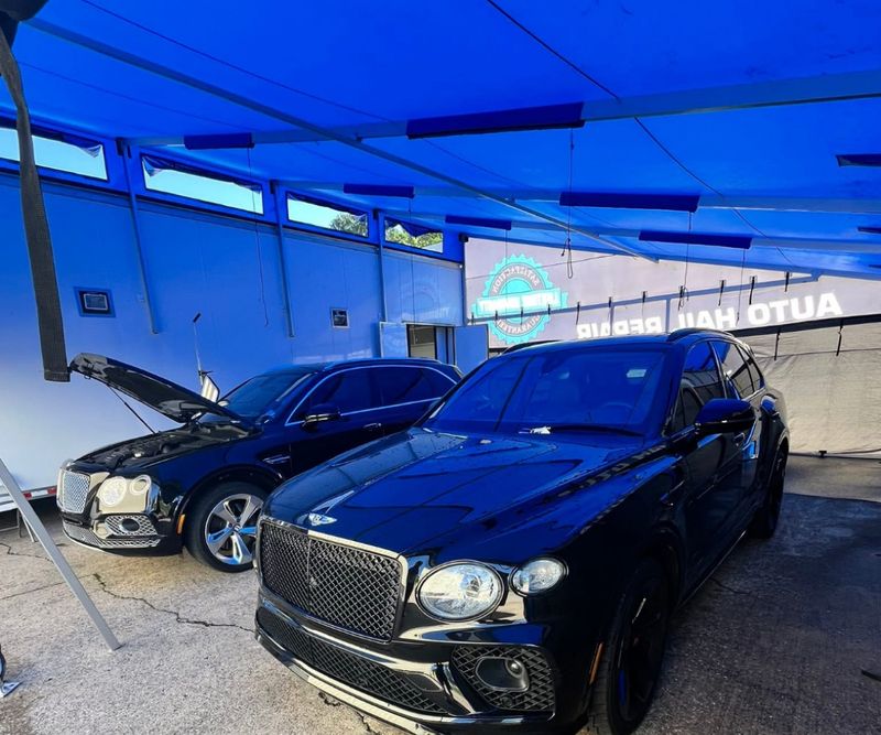 Auto Hail Repair mobile workshop inside a DMP full enclosure, with two luxury SUVs under the blue roof