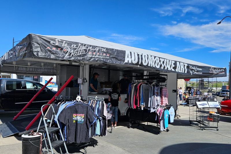 Shannon Watts Automotive Art vendor trailer awning with apparel and prints set out underneath