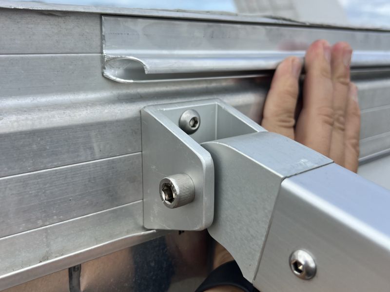 Close-up of a DMP machined bracket joining the aluminum awning frame to the trailer rail