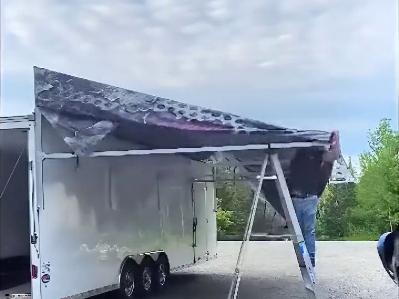 Kyle Wiejak raising the aluminum frame and pulling out the printed fabric of his DMP race trailer awning