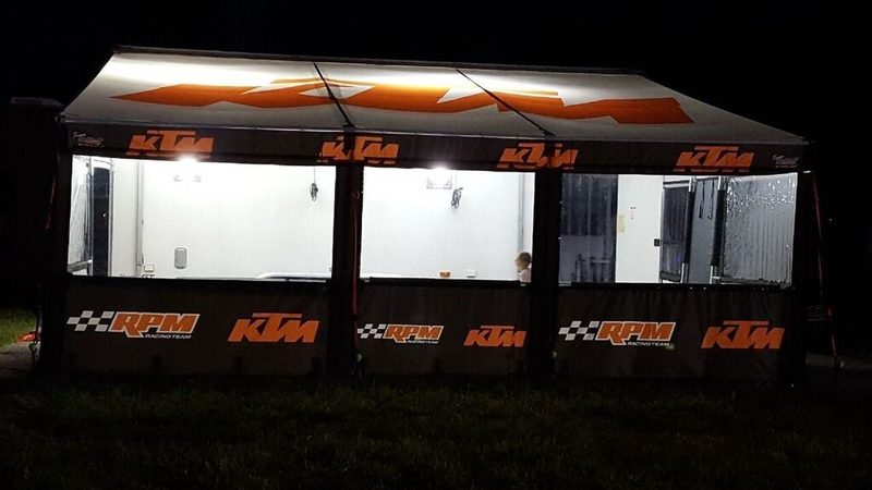 KTM RPM Racing motocross team trailer awning lit up at night