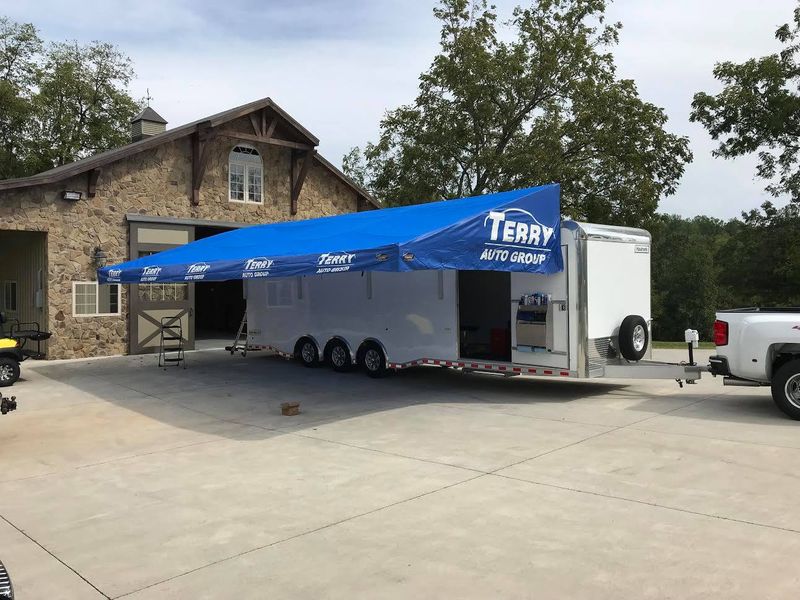 Blue printed Terry Auto Group awning on an enclosed car trailer